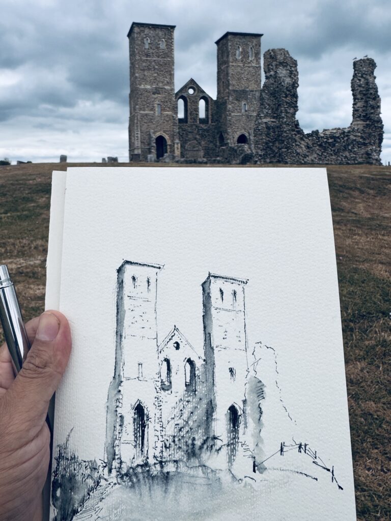 Completed line-and-wash sketch held against Reculver Towers beneath a cloudy sky