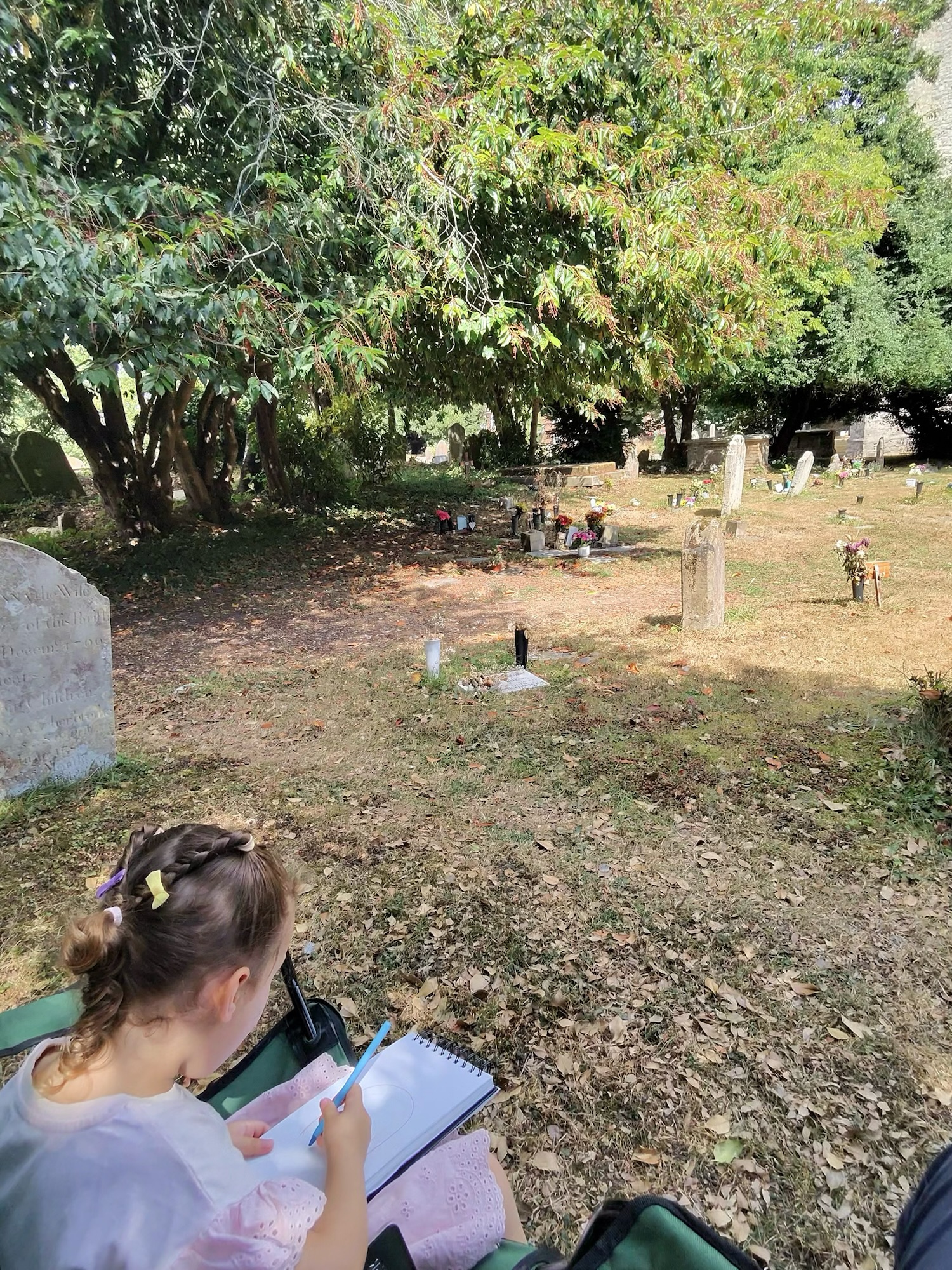 Sketching St Margaret’s Church in Rainham with My Little Girl 4 Young child drawing in a sketchbook while seated in St Margaret’s Church churchyard.